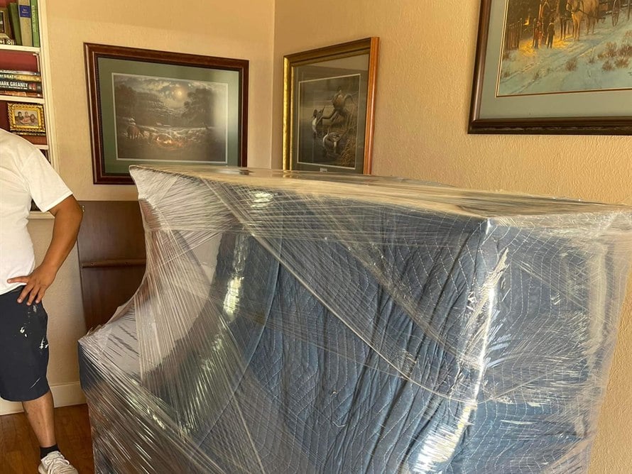 Collins Family Movers crew shrink-wrapping an upright piano for a residential move